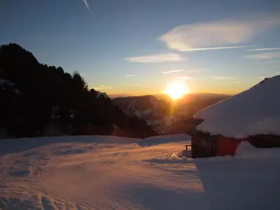 a snow covered mountain with the sun setting in the background at Residence La Planta in Ortisei