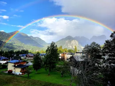 a rainbow in the sky over a town with houses at Appartamenti Dolomiti in Colcerver