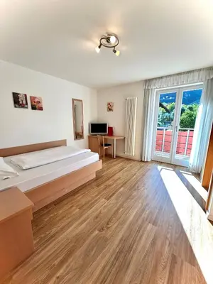 a hotel room with a bed and a television at B&B Garni Erika in Termeno