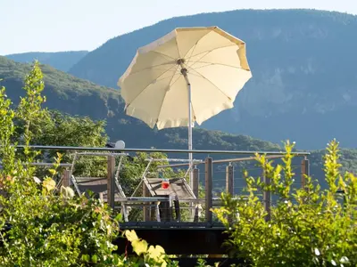 a pool with chairs and umbrellas next to a building at B&B Garni Erika in Termeno