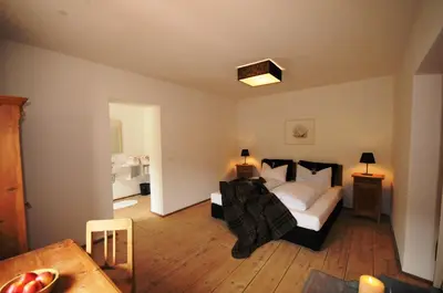 a bedroom with a bed and a room with a table at Steinwandterhof in Braies