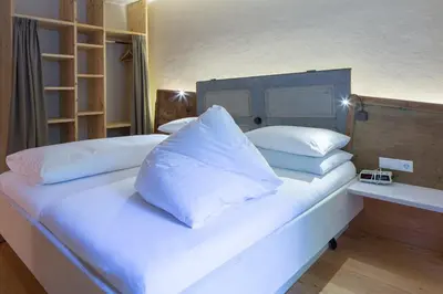 a large bed with white pillows on top of it at Frida am Wald in Rasùn di Sotto