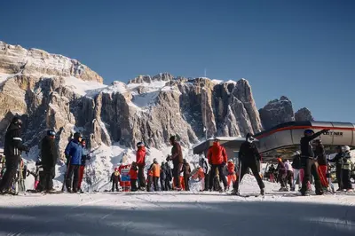 a group of people on skis in front of a mountain at Hotel Pordoi Passo Pordoi Vegetarian Hotel in Canazei