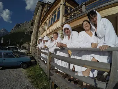 a group of women in white robes leaning on a fence at Hotel Pordoi Passo Pordoi Vegetarian Hotel in Canazei