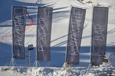 a group of flags on poles in the snow at Hotel Pordoi Passo Pordoi Vegetarian Hotel in Canazei