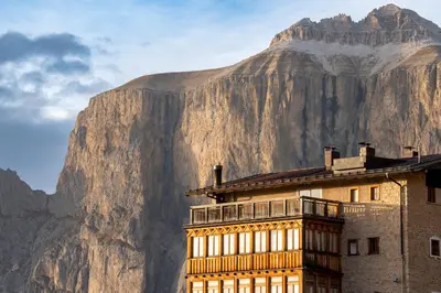 a building with a mountain in the background at Hotel Pordoi Passo Pordoi Vegetarian Hotel in Canazei