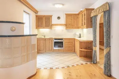 a kitchen with wooden cabinets and a tile floor at App. Désirée in San Vigilio Di Marebbe