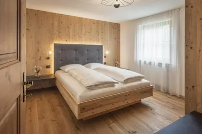 a bedroom with a large bed with a wooden wall at App. Désirée in San Vigilio Di Marebbe