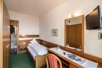 a hotel room with a bed and a desk and a television at Pension Grafenau in Schenna