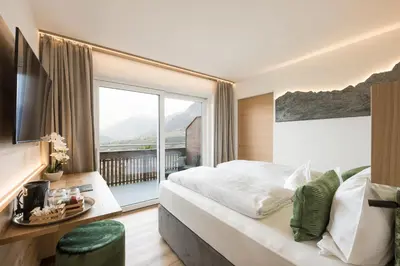 a bedroom with a large bed and a large window at Pension Grafenau in Schenna