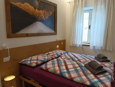 a bed with a plaid comforter in a bedroom at Casa Volcan in Tesero