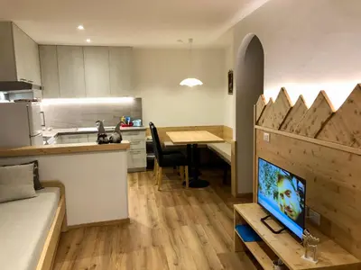 a kitchen and a living room with a tv and a table at Casa Volcan in Tesero