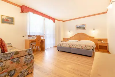a bedroom with a bed and a desk at Hotel Garni la Stua in Selva di Cadore