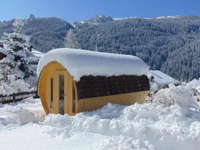 a small building covered in snow in the snow at Hotel Garni la Stua in Selva di Cadore