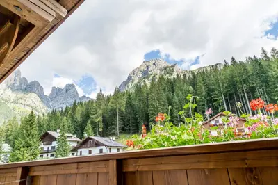 a balcony with a view of mountains and flowers at Hotel Garni la Stua in Selva di Cadore