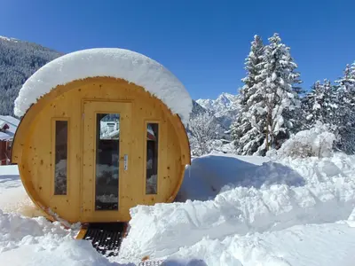 a wooden cabin in the snow with snow covered trees at Hotel Garni la Stua in Selva di Cadore