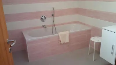 a pink bathroom with a tub and a stool at Villetta Muncion in Pozza di Fassa
