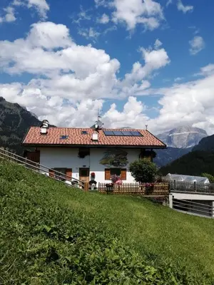 a house on top of a hill with a green field at Villetta Muncion in Pozza di Fassa