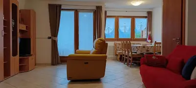 a living room with a red couch and a table at Villetta Muncion in Pozza di Fassa