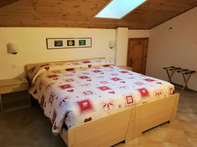 a bedroom with a bed with a red and white blanket at Maso Sveseri in Montesover