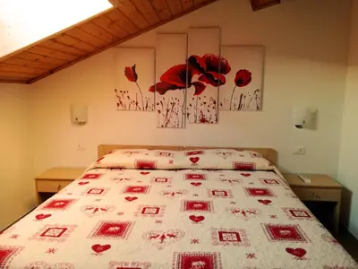 a bedroom with a bed with red flowers on it at Maso Sveseri in Montesover