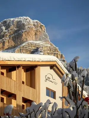 a building covered in snow with a mountain in the background at Residence Settsass in Colfosco