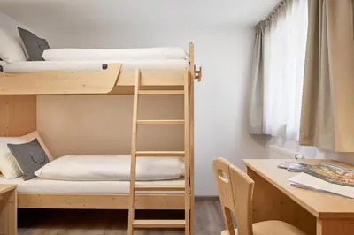 a dorm room with bunk beds and a desk at Residence Settsass in Colfosco