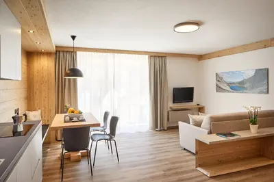 a kitchen and a living room with a couch and a table at Residence Settsass in Colfosco