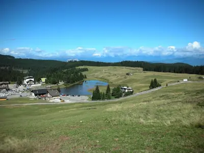 a view of a field with a lake in the middle at DOLOMITI appart&rooms in Varena