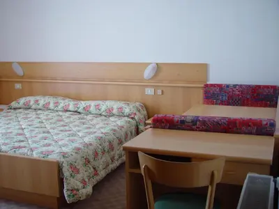 a bedroom with a bed and a desk and a table at DOLOMITI appart&rooms in Varena