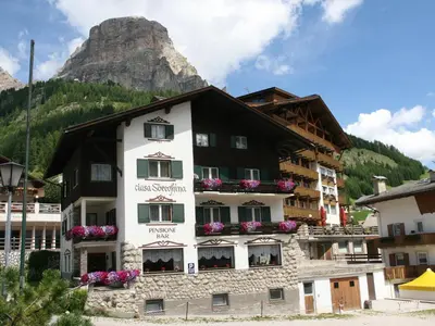 a white and black building with a mountain in the background at Ciasa Soreghina in Colfosco