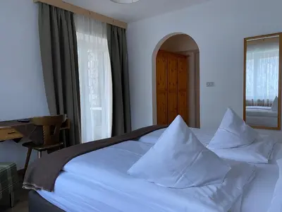 a bedroom with a bed with white sheets and pillows at Ciasa Soreghina in Colfosco