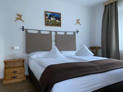 a bedroom with a large bed with white sheets at Ciasa Soreghina in Colfosco