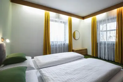 a bedroom with two beds and two windows at Kronplatz Lodge Dolomites in San Vigilio Di Marebbe