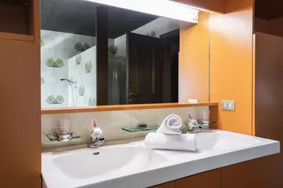 a bathroom with a white sink and a large mirror at Kronplatz Lodge Dolomites in San Vigilio Di Marebbe