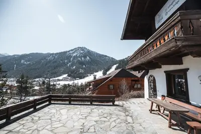 a building with a bench on a patio with a mountain at Kronplatz Lodge Dolomites in San Vigilio Di Marebbe
