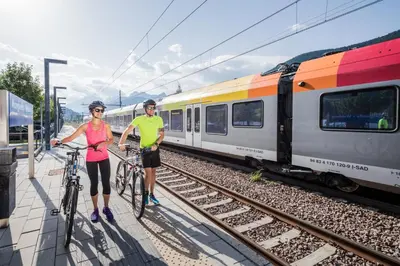 two people with bikes standing next to a train at Hotel Dolomiten in Monguelfo