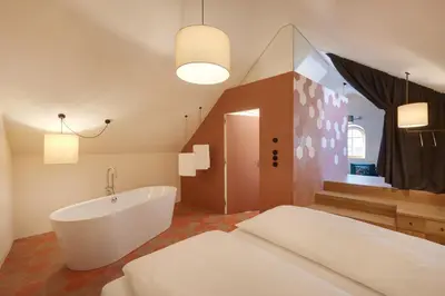 a bathroom with a white tub and a large window at Goldengel Design - Suiten im historischen Ortskern von Kaltern in Caldaro
