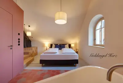 a bedroom with a bed and a bath tub at Goldengel Design - Suiten im historischen Ortskern von Kaltern in Caldaro