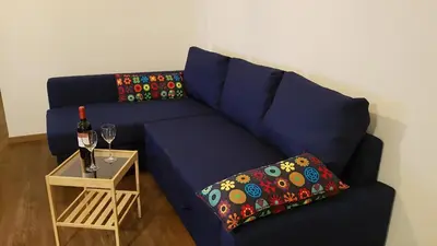 a blue couch with a pillow and a table with a wine glass at Dolomitica, nuovo, fino a 6 Persone in Vols am Schlern