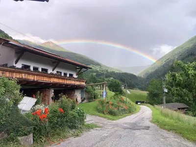 a rainbow over a road next to a house at Martlerhof Urlaub auf dem Bauernhof in Campo di Trens