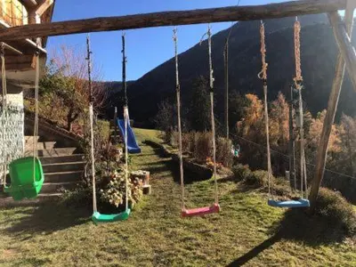 a playground with swings in a yard with a mountain at Martlerhof Urlaub auf dem Bauernhof in Campo di Trens