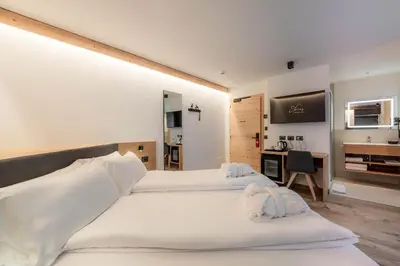 a hotel room with two beds and a desk at Spires Hotel in Canazei