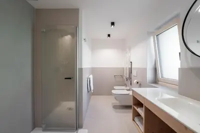 a bathroom with a shower and two toilets at Spires Hotel in Canazei