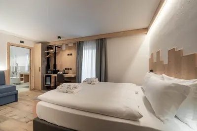 a bedroom with a large white bed and a living room at Spires Hotel in Canazei