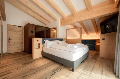 a bedroom with a bed and a wooden floor at Spires Hotel in Canazei