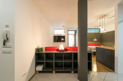 an open kitchen and living room with a red couch at Laubenapartment in Merano