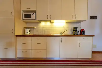 a kitchen with white cabinets and a microwave at Chalet Alpina in Ortisei