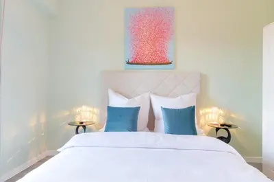 a bedroom with a white bed with blue pillows at Penthouse Jolanda Meran-o in Merano