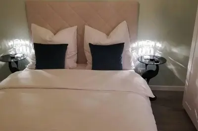 a bedroom with a large white bed with two tables at Penthouse Jolanda Meran-o in Merano